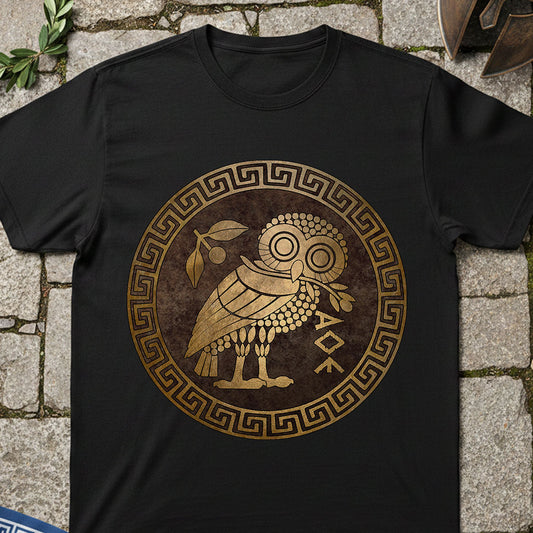 Athens Owl Black t-shirt with a gold owl design on a stone surface
