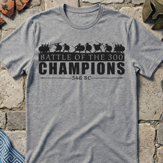 Gray t-shirt with 'Battle of the 300 Champions' design on a stone wall background