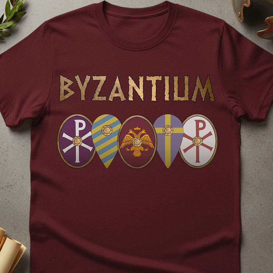 Maroon t-shirt with 'Byzantium' text and symbols on a gray surface.