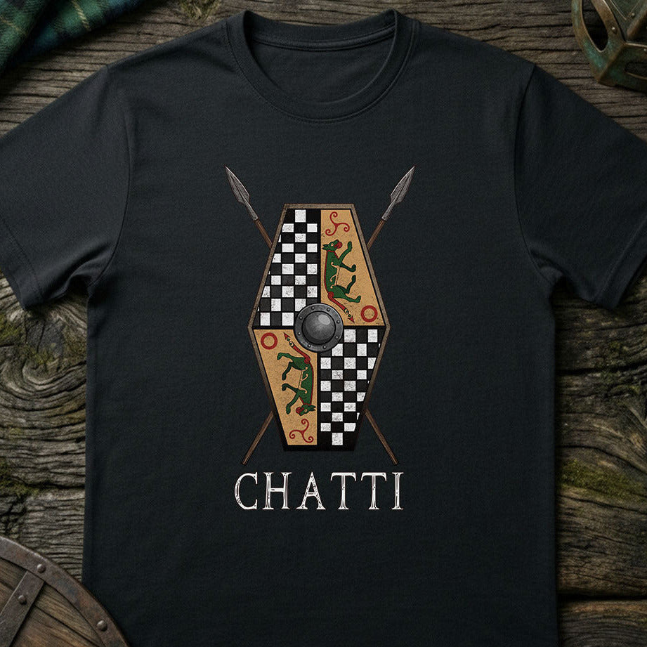 Black t-shirt with a shield and spear design and 'CHATTI' text on a wooden surface.