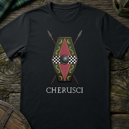 A black short-sleeve t-shirt with a graphic of a red and gold shield, crossed spears, and the word 'CHERUSCI' printed below, displayed flat on a rustic wooden background.
