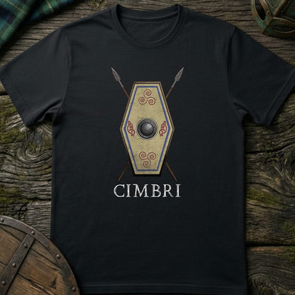 A black short-sleeve t-shirt laid flat on a rustic wooden surface, featuring a central graphic of a Viking-style Cimbrian shield with crossed spears behind it and the word 'CIMBRI' printed below in white.