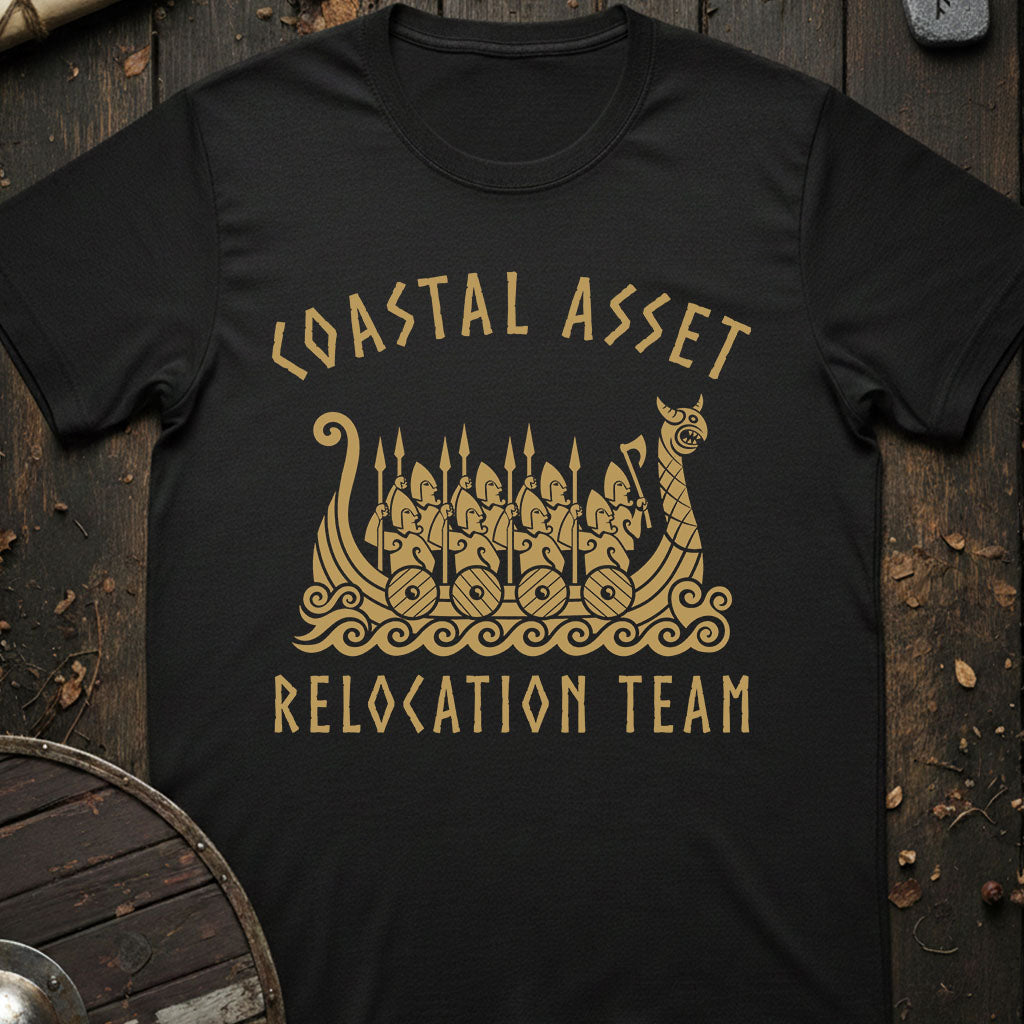 Black t-shirt with gold graphic and text 'Coastal Asset Relocation Team' on a wooden background