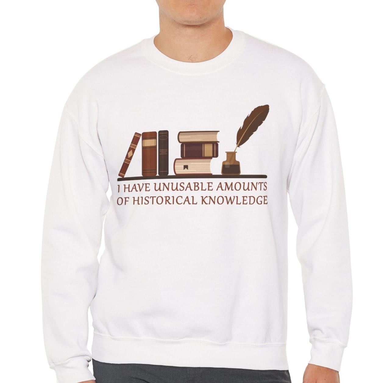 A man wearing a white crewneck sweatshirt with a brown graphic of books, an inkwell, and a quill, with the text 'I HAVE UNUSABLE AMOUNTS OF HISTORICAL KNOWLEDGE' printed on the front.