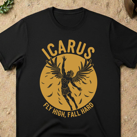 Black t-shirt with 'ICARUS FLY HIGH, FALL HARD' design on a sandy surface.