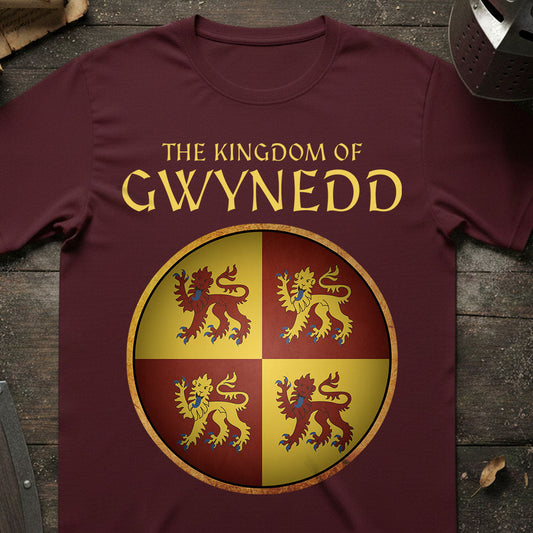 Maroon t-shirt with 'The Kingdom of Gwynedd' design featuring four lions on a wooden surface.