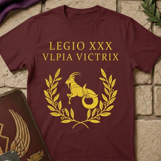 Maroon t-shirt with gold Roman numeral design Legio XXX Ulpia Victrix Roman Legion on a stone surface