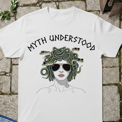 White t-shirt with graphic design of Medusa and 'MYTH UNDERSTOOD' text on a stone surface.