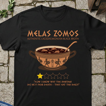 Black t-shirt with 'Melas Zomos' design featuring a bowl of soup on a stone surface.