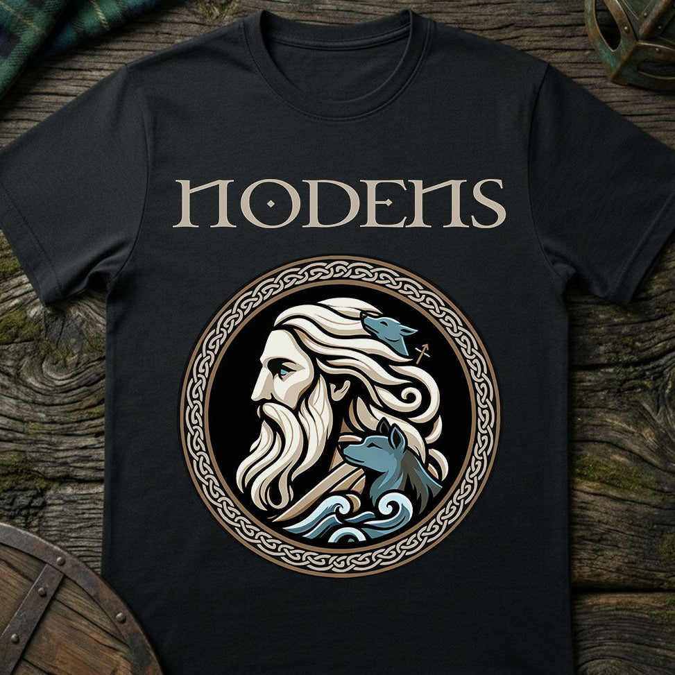 Black t-shirt with a graphic design of a bearded man and two wolves, featuring the word 'Nodens', on a wooden surface.