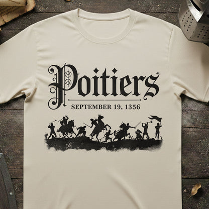Beige t-shirt with black graphic and text 'Poitiers September 19, 1356' on a wooden surface.
