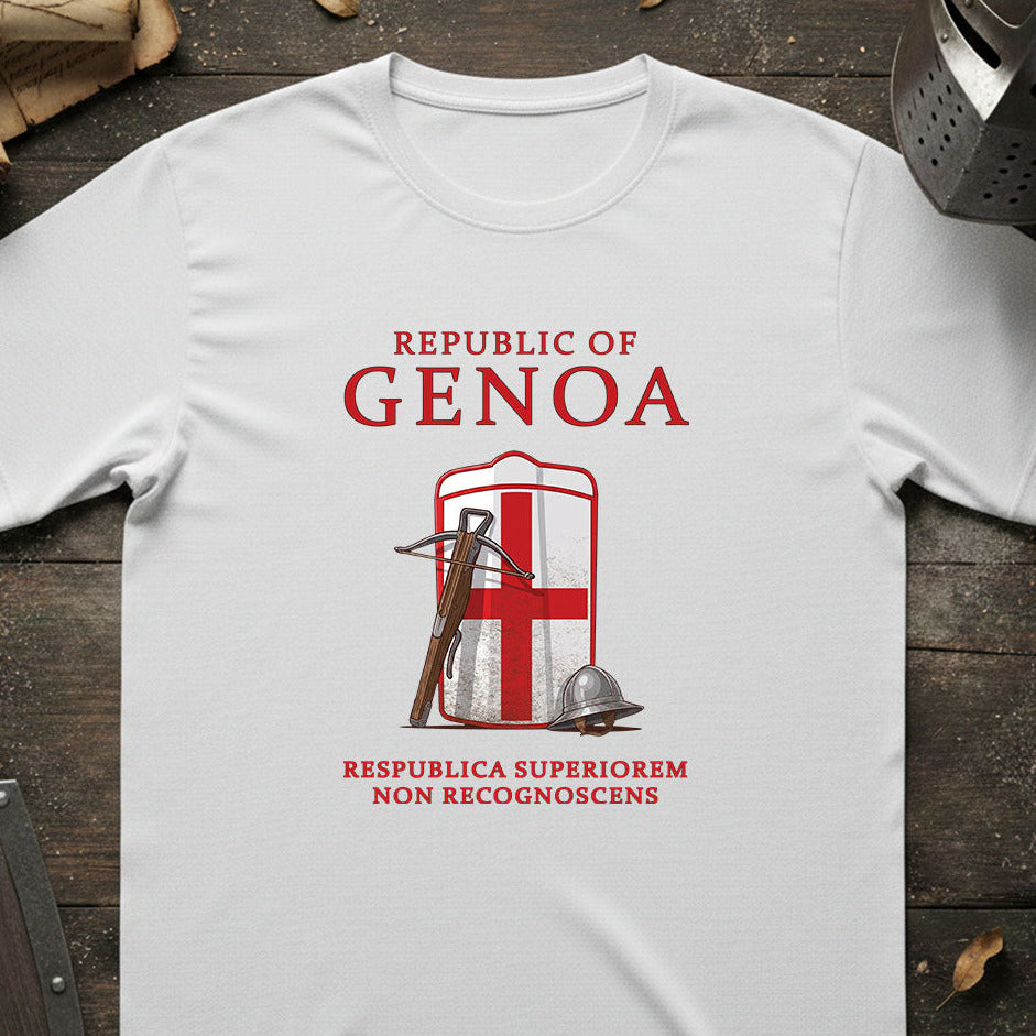 A white short-sleeve T-shirt laid flat on a dark wooden surface, featuring a red and white Genoa graphic with the words 'REPUBLIC OF GENOA' and a historical flag design. Decorative props including a helmet, scroll, and shield are partially visible around the edges.