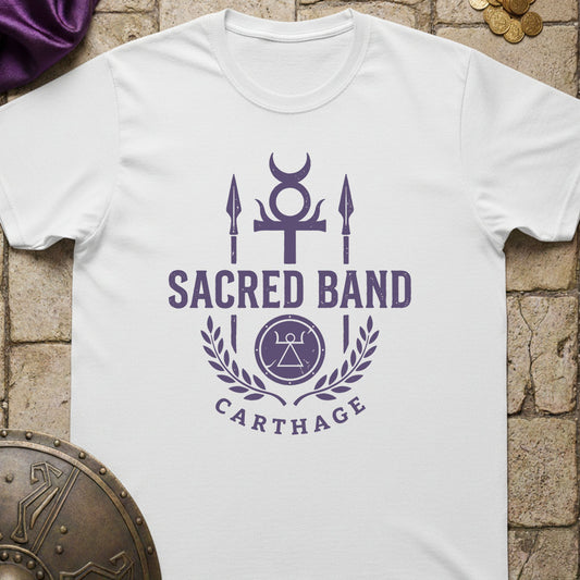 White t-shirt with purple 'Sacred Band Carthage' design on a stone surface.