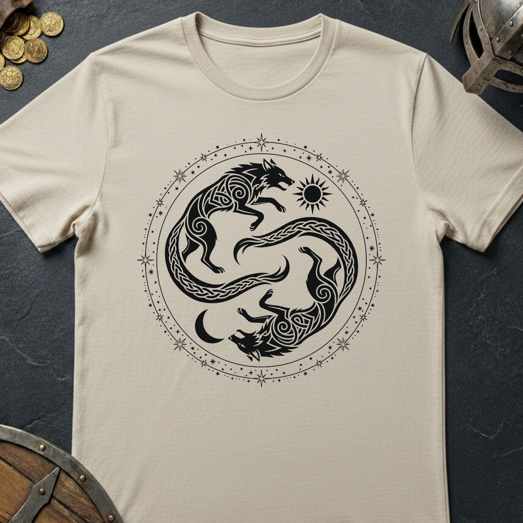 A beige short-sleeve t-shirt with a black circular graphic of two warring wolves and a sun, laid flat on a dark slate background with decorative props.