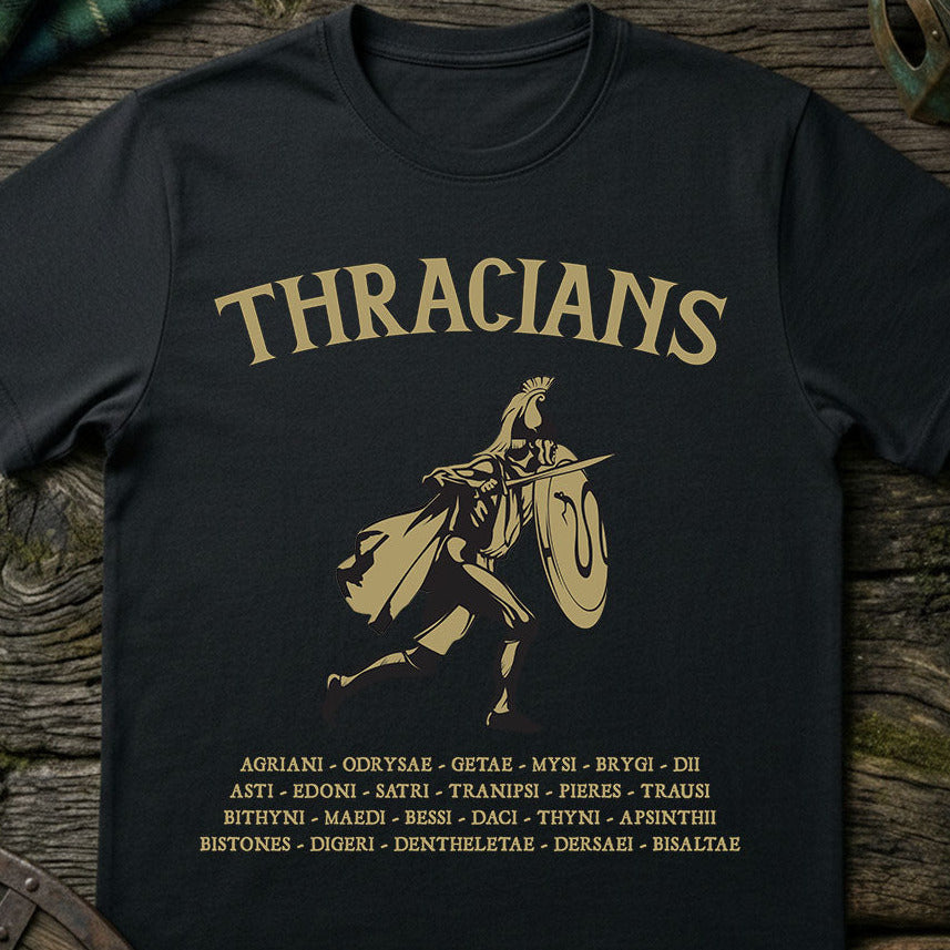 Black t-shirt with gold 'THRACIANS' text and warrior silhouette on a wooden surface.