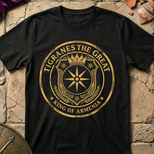 Black t-shirt with gold emblem and text 'Tigranes the Great, King of Armenia' on a stone surface.