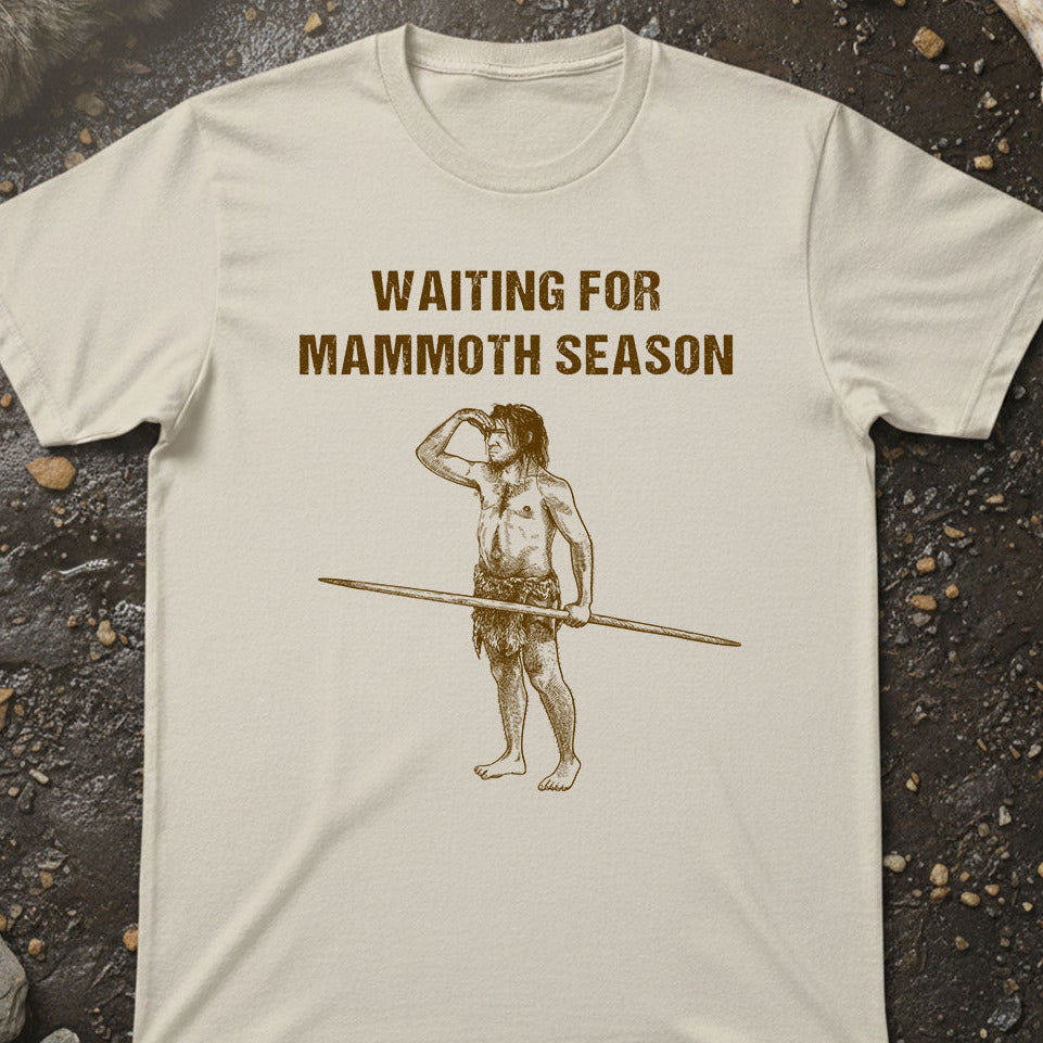 T-shirt with a graphic of a caveman holding a spear and text 'Waiting for Mammoth Season' on a textured surface.