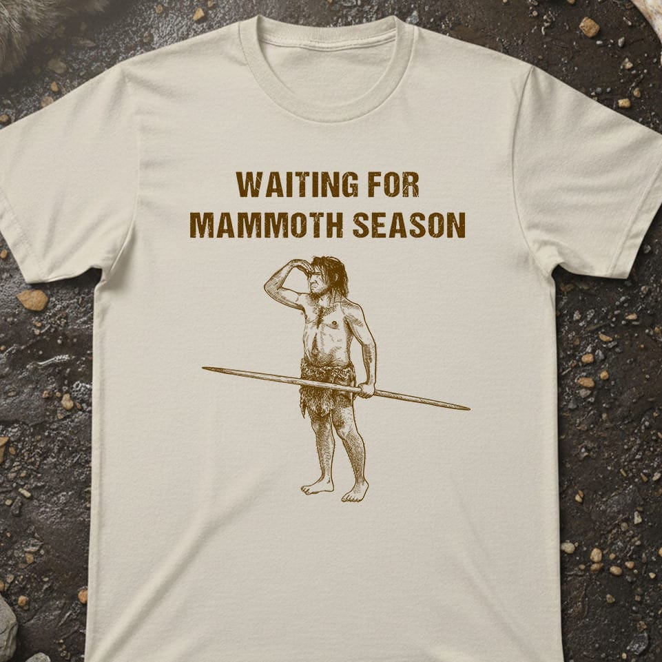 T-shirt with a graphic of a caveman holding a spear and text 'Waiting for Mammoth Season' on a textured surface.