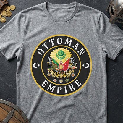 Gray t-shirt with Ottoman Empire logo on a dark surface with coins and a shield.